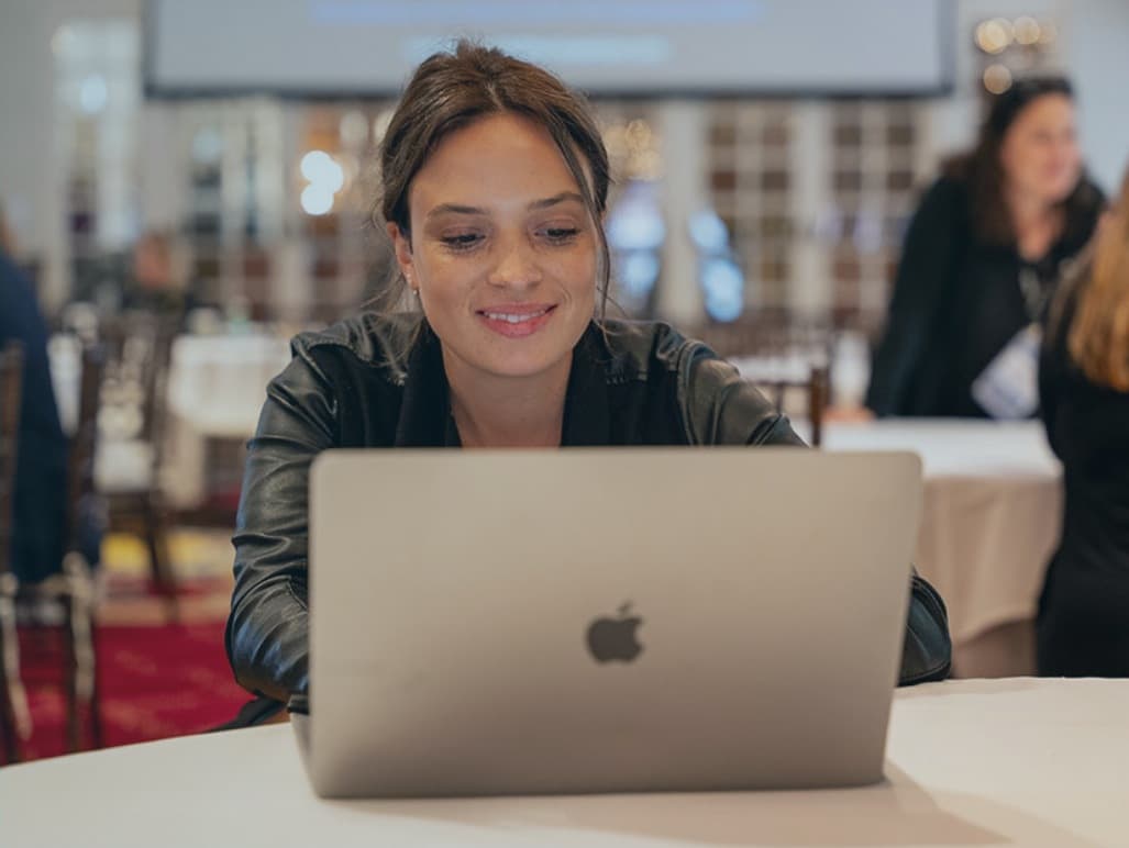 a woman smiling while looking at a laptop computer
