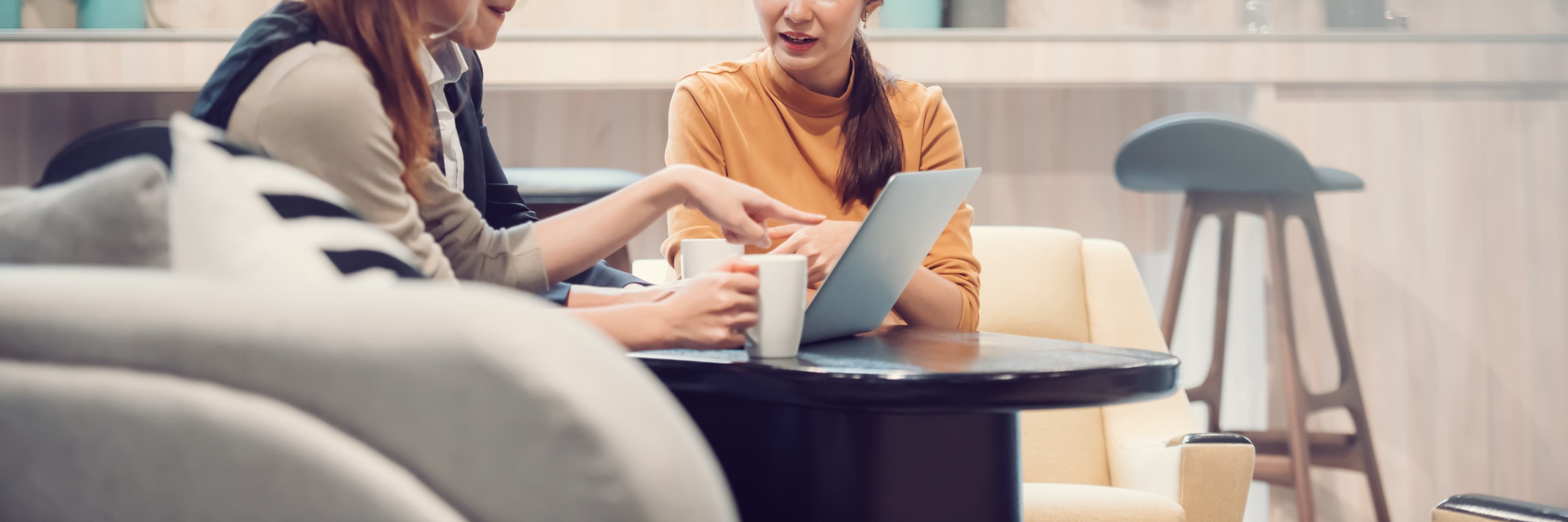 women at small table working on laptop